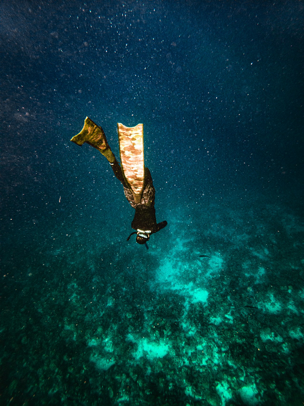 An elite freediver descending into dark blue water